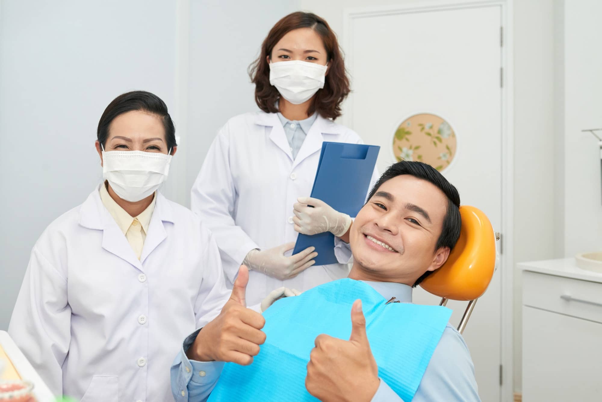 Smiling patient and doctors in dental office